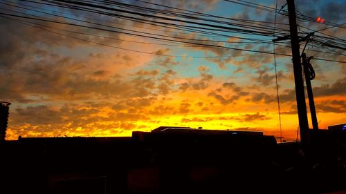 Low angle view of silhouette electricity pylon against sky during sunset