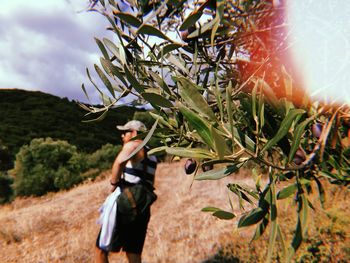 Woman standing by tree against sky