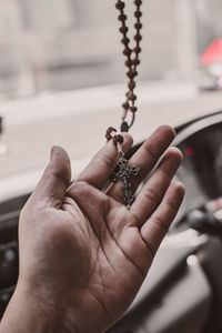 Close-up of hand holding cross against blurred background