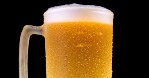 Close-up of beer glass against black background