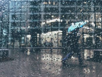 Man walking on footpath seen through wet car window during rainy season