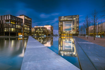 Reflection of illuminated buildings in swimming pool against sky, hq thyssen,  essen 