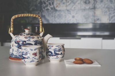 Close-up of crockery by biscuits on table in kitchen