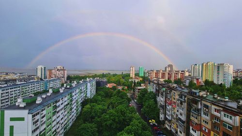 Rainbow over buildings in city against sky