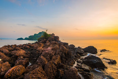 Rock formation on beach against sky during sunset