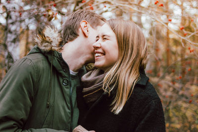 Smiling couple embracing against trees