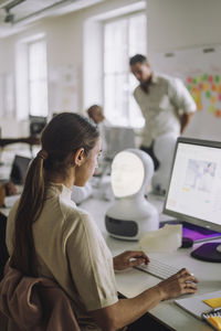 Side view of female student using computer while sitting at desk