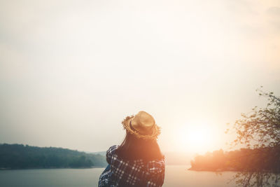 Woman standing by tree against sky during sunset