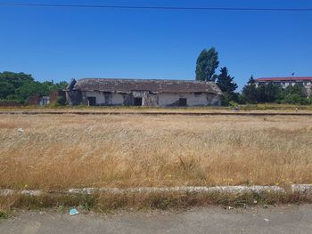 Abandoned house on field against clear blue sky