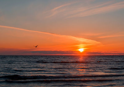 Scenic view of sea against cloudy sky during sunset