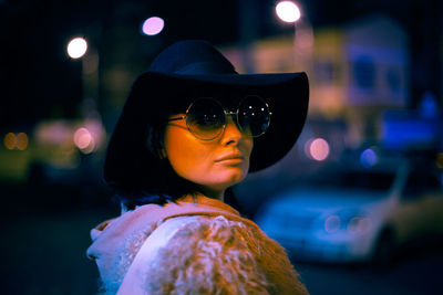 Portrait of woman wearing sunglasses in city at night