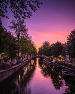 Canal amidst trees against sky during sunset