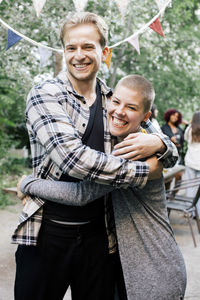 Portrait of young man embracing female friend at dinner party in back yard