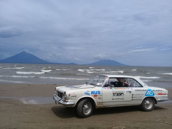 Vintage car on beach against sky