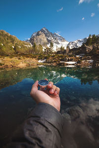 Man with a compass in his hand in the high mountains near a clear mountain lake. travel concept