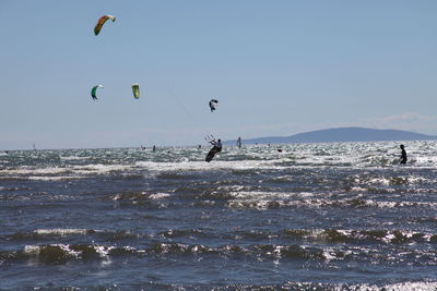 People paragliding over sea against sky