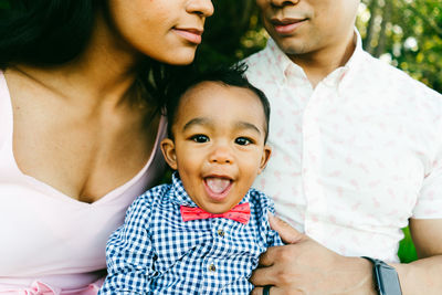 Cropped closeup portrait of a baby boy sitting on his parent's laps