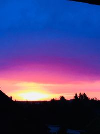 Silhouette trees against dramatic sky during sunset