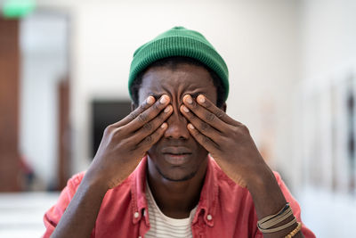 Tired stressed african guy student sitting in library massaging eyes feeling unmotivated to study