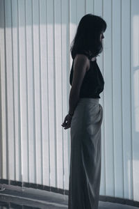 Rear view of woman standing against wall