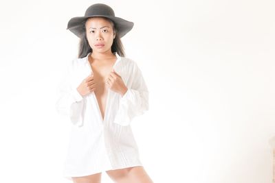 Portrait of beautiful young woman standing against white background
