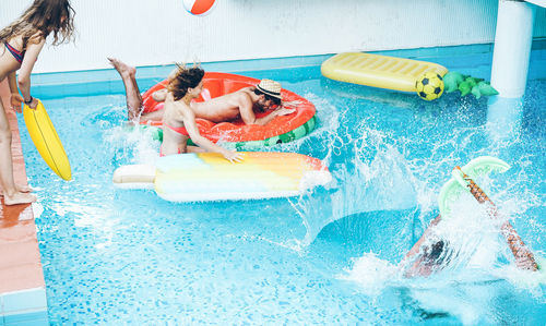 Friends enjoying on pool rafts in swimming pool