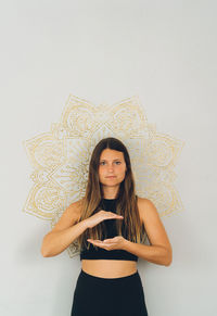 Portrait of beautiful young woman standing against wall