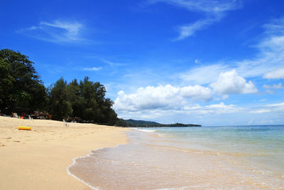The view on a beach with sea, blue sky and white sand on a sunny day.