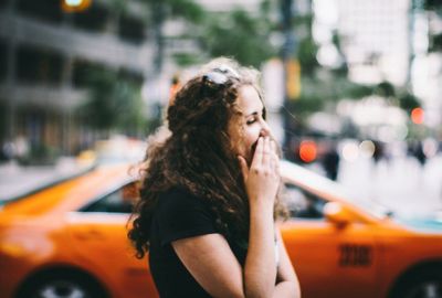 Young woman covering mouth with hands on city street