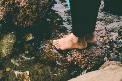 A model standing on the rocks by the river 