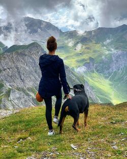 Rear view of man with dog looking at mountains