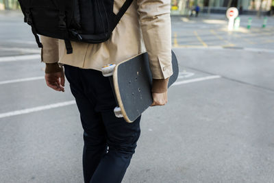 Man with backpack and skateboard in the city, partial view