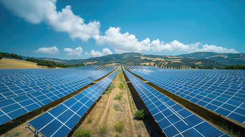 Solar panels cover a vast land lot on a sloping plain with mountains in the background