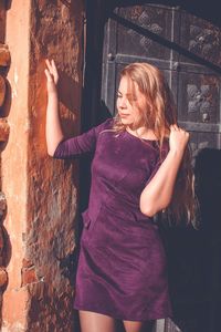 Young woman standing against wall