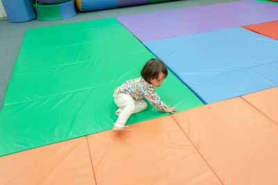 High angle view of girl playing on carpet in kindergarten