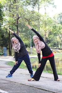Sisters wearing hijab while exercising by lake at park