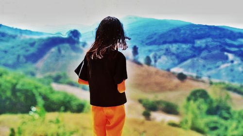 Rear view of woman standing against mountain