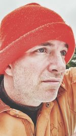 Close-up of thoughtful man wearing orange knit hat