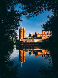 Reflection of building in lake against sky at dusk