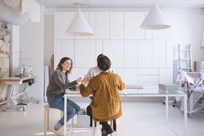 Female design professionals are discussing at desk in workshop