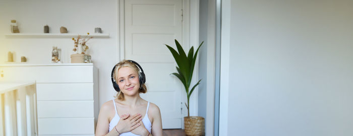 Portrait of young woman standing at home