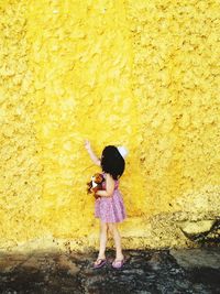 Girl standing against yellow wall