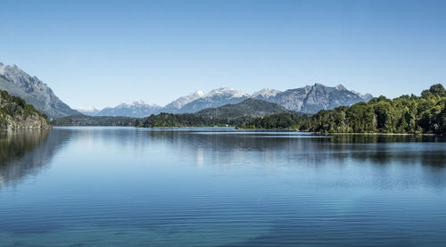 Scenic view of lake and mountains against clear blue sky