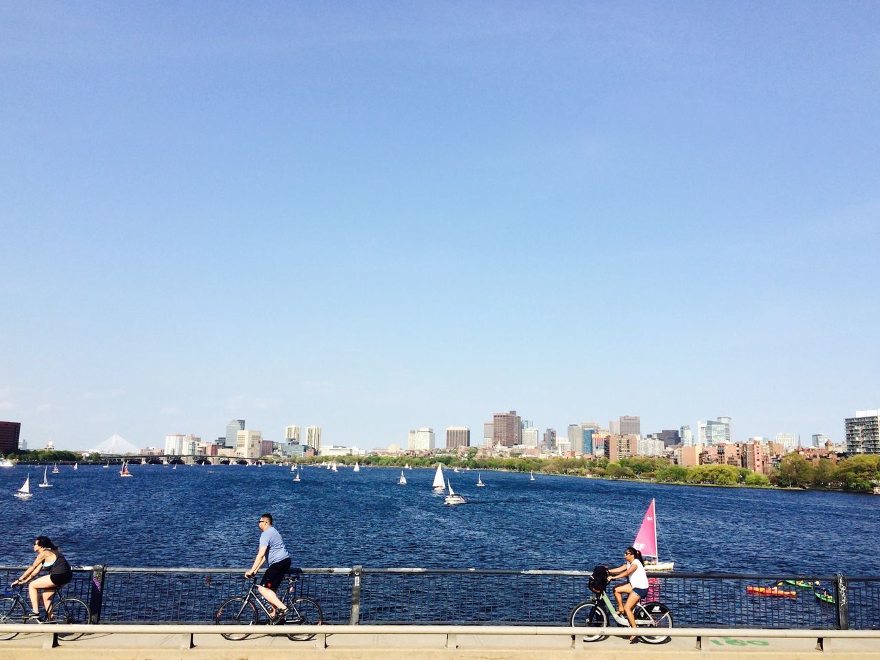 water, clear sky, copy space, building exterior, built structure, city, architecture, lifestyles, men, nautical vessel, river, railing, leisure activity, transportation, cityscape, sea, sitting, person