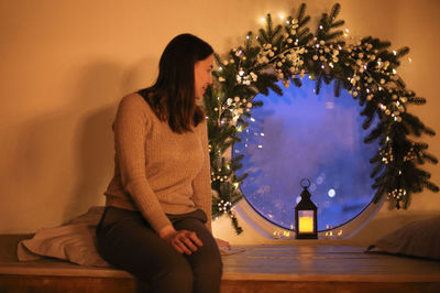 Young woman sitting on christmas tree