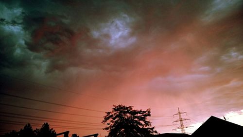 Low angle view of electricity pylon against cloudy sky