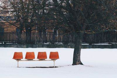 Empty chairs on snow covered field during winter