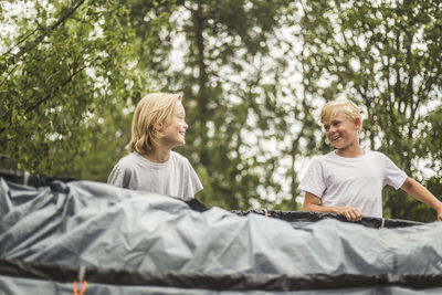 Excited brother and sister pitching tent together at camping site
