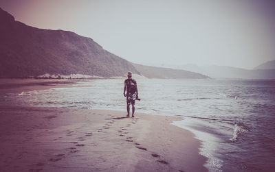 Rear view of woman on beach against sky