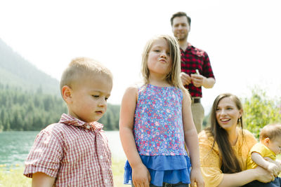 Straight on view of a young girl making a silly face with family